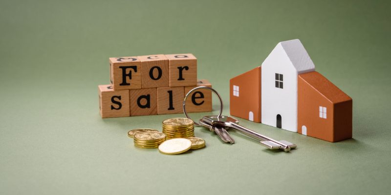 A small wooden house and keys as an idea for investing in your own home and achieving the goal of buying real estate. Background for your idea