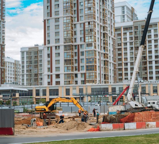 Unrecognizable workers and technic work at modern construction site of appartment recidential building in city.